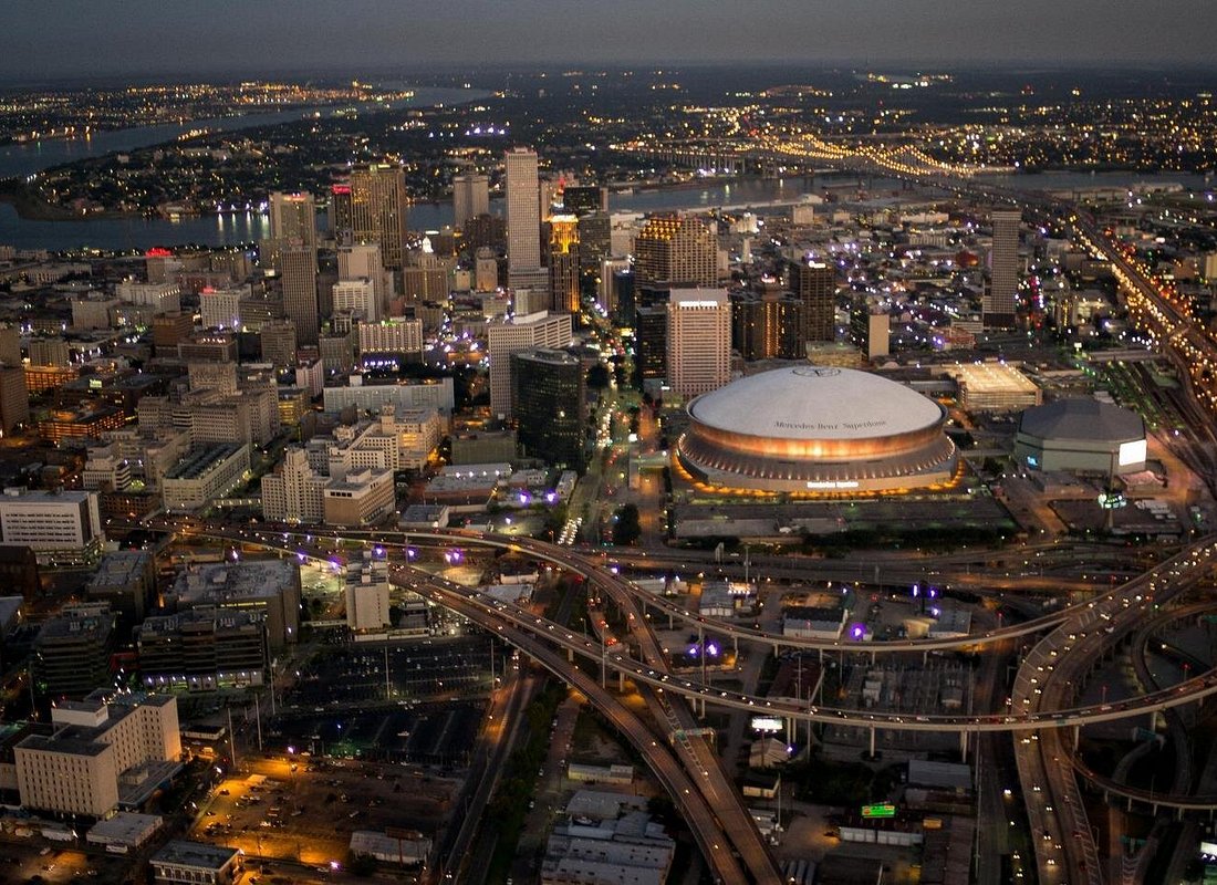 Aerial view of the New Orleans skyline at dusk, showing the Superdome and downtown