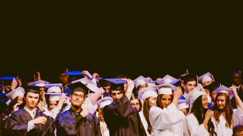 Black graduates in caps and gowns celebrating at commencement